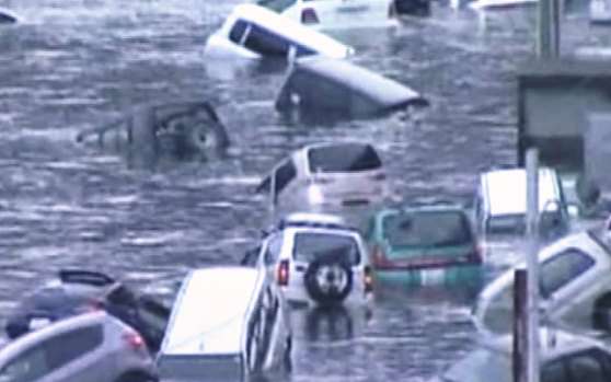 Автомобили жителей находятся в воде после цунами 