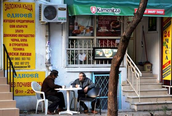 Мужчины болгары пьют раки в уличном кафе 